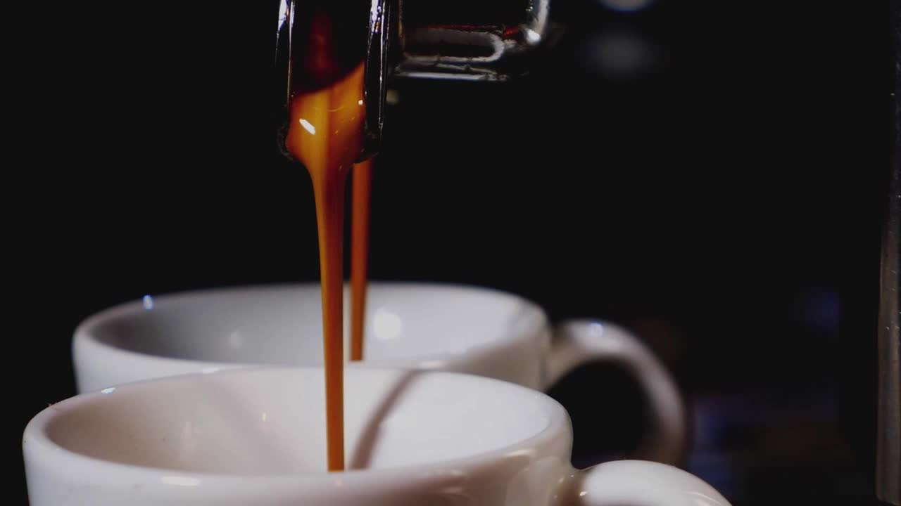 Espresso pouring into white coffee cups