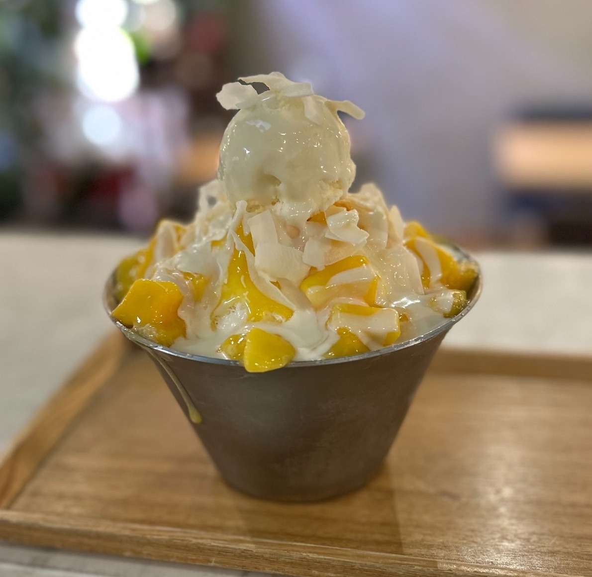 Mango bingsu with ice cream and mango pieces on a wooden tray